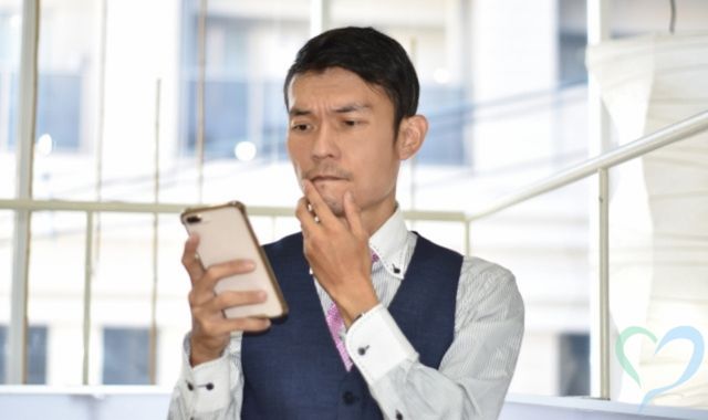 スマートフォンで社内メールを確認するスーツ姿の男性