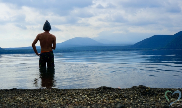 テントサウナ後湖畔で水を浴びる男性