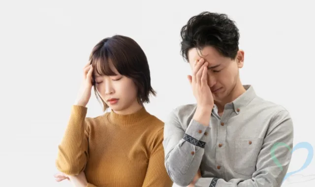 頭を押さえて考える男女