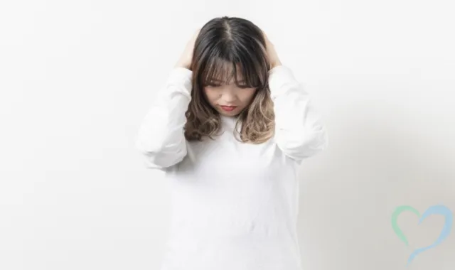 白いシャツの女性が頭を抱えて困っている様子