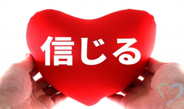 信じると書かれたハートを手に持つ画像