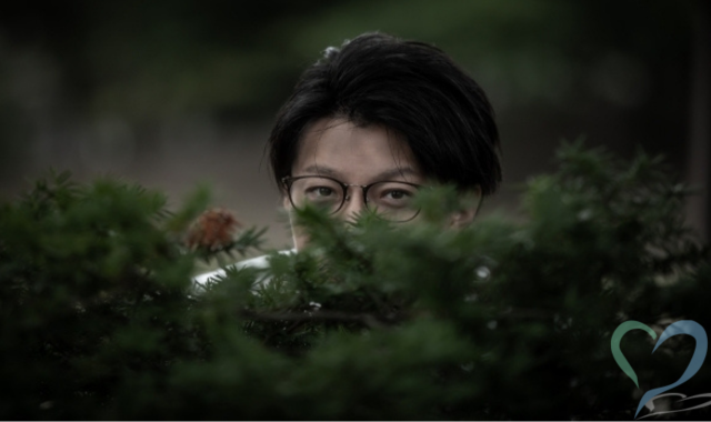 草むらから覗いてプライバシー侵害をする男性