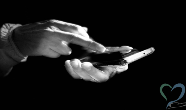 暗闇の中でスマホを操作する手