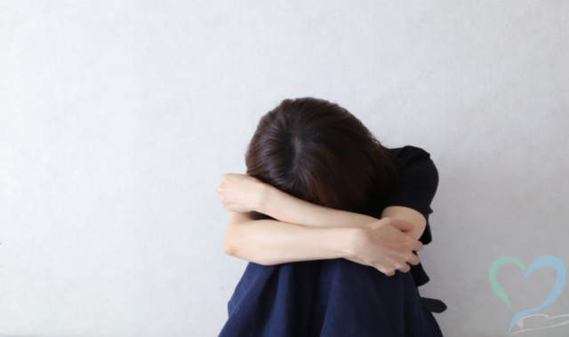 膝を抱えてうずくまる自己評価が低い女性