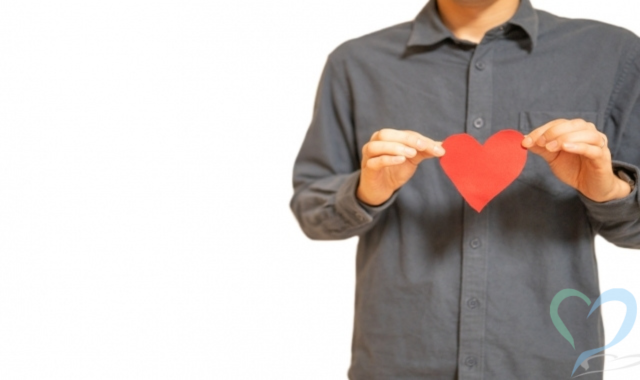 ハート型の紙を持ったシャツの男性